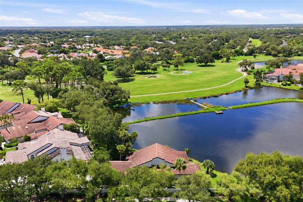 An aerial view of a residential neighborhood featuring houses, a golf course, and a lake — 4300 CAMINO MADERA, SARASOTA, FL