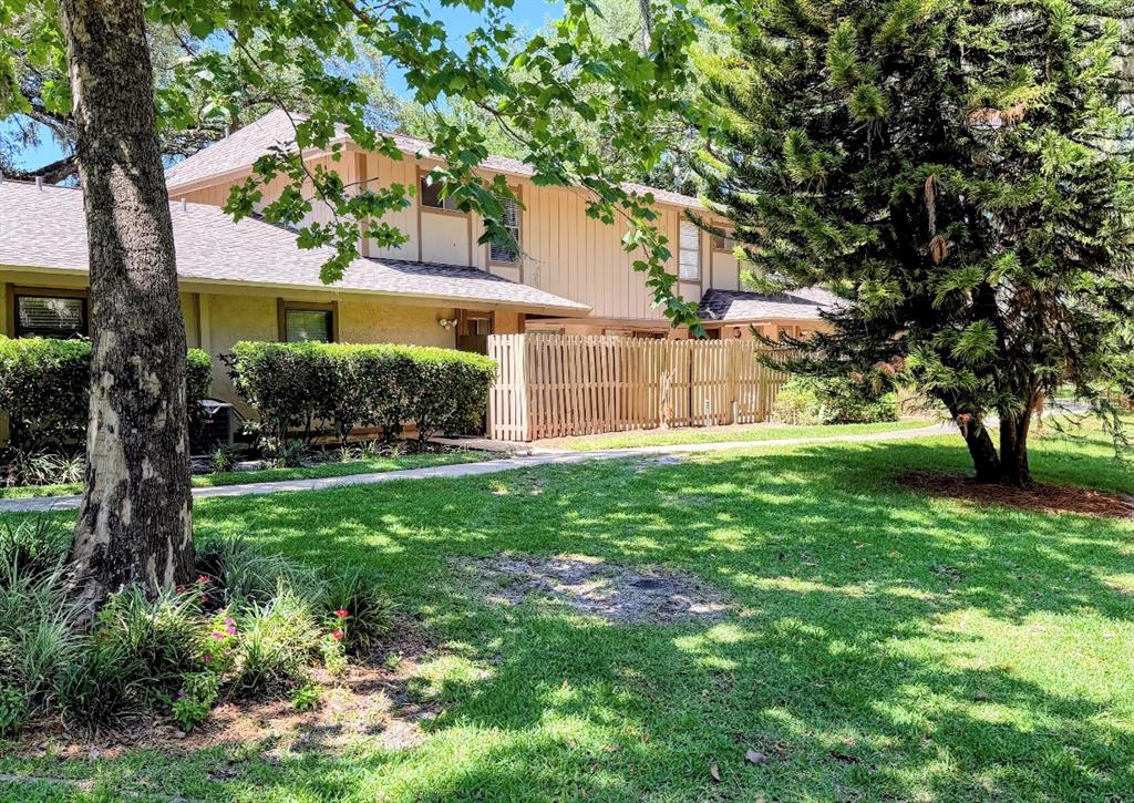 A two-story townhouse exterior with a wooden privacy fence and a grassy front yard — 3205 DEER COURT, BRANDON, FL