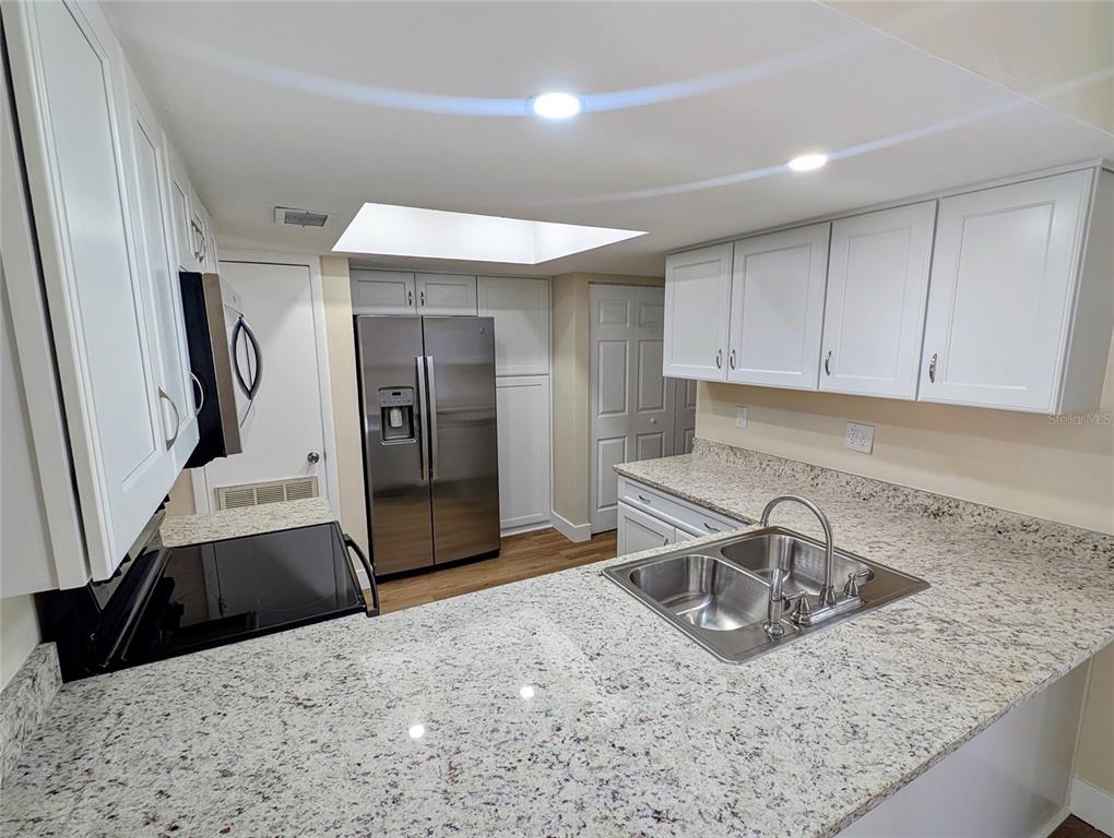 A kitchen features white cabinets, granite countertops, stainless steel appliances, and a skylight — 3205 DEER COURT, BRANDON, FL