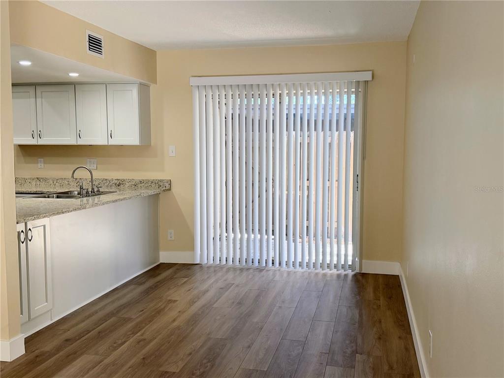 A dining area with wood-look flooring, light-colored walls, and a sliding glass door with blinds — 3205 DEER COURT, BRANDON, FL