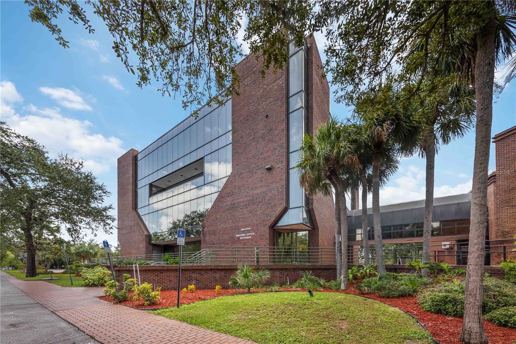 A multi-story brick and glass office building stands surrounded by palm trees and landscaping — 1620 TAMIAMI TRAIL, PORT CHARLOTTE, FL