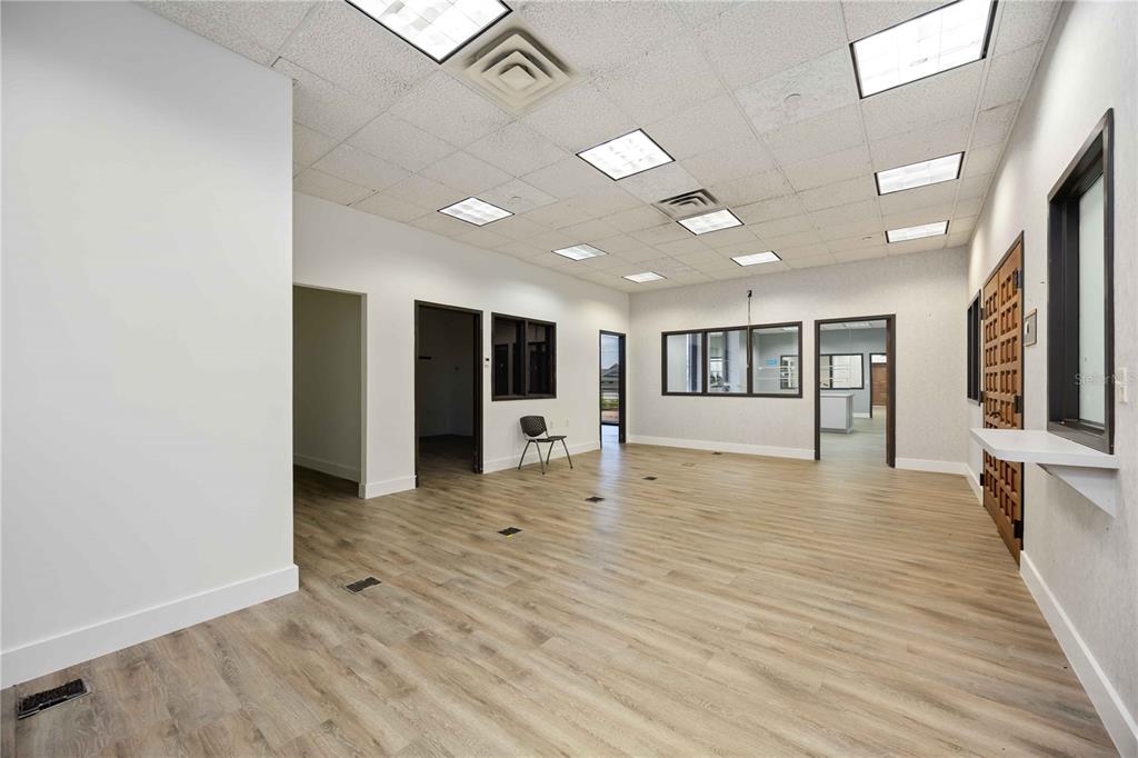 An empty office space with wood-look flooring, drop ceiling panels, and several interior doorways — 1620 TAMIAMI TRAIL, PORT CHARLOTTE, FL