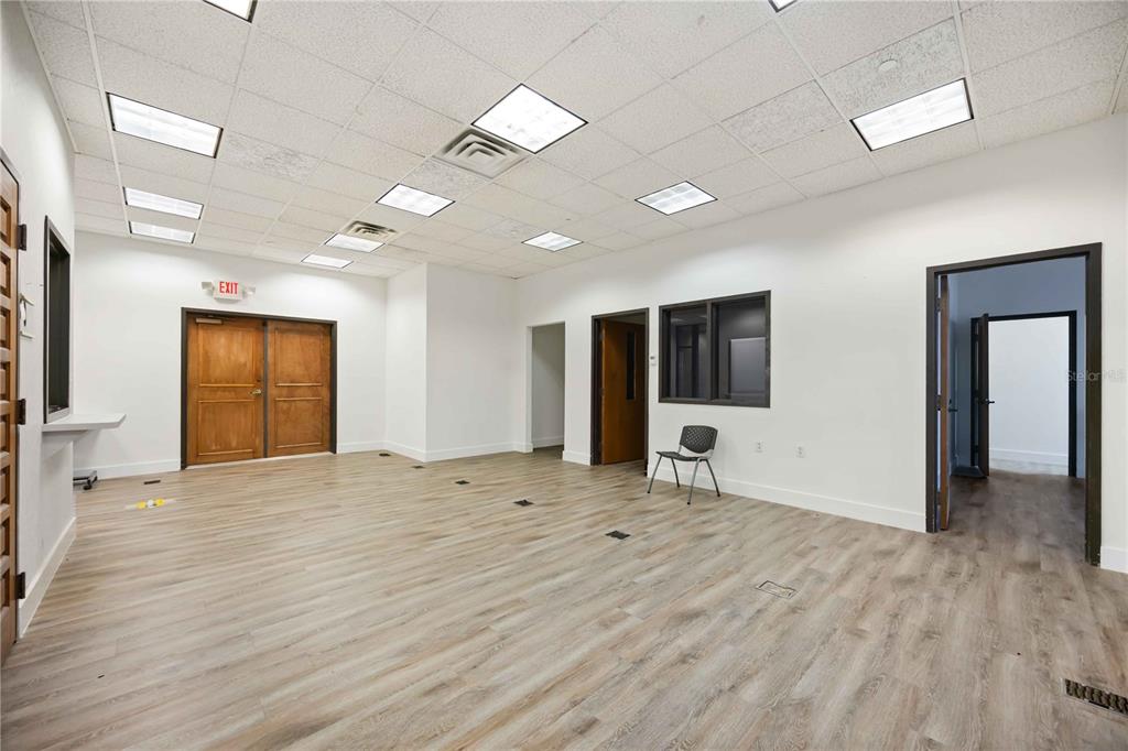 An empty office space with wood-look flooring, white walls, a drop ceiling, and multiple doorways — 1620 TAMIAMI TRAIL, PORT CHARLOTTE, FL