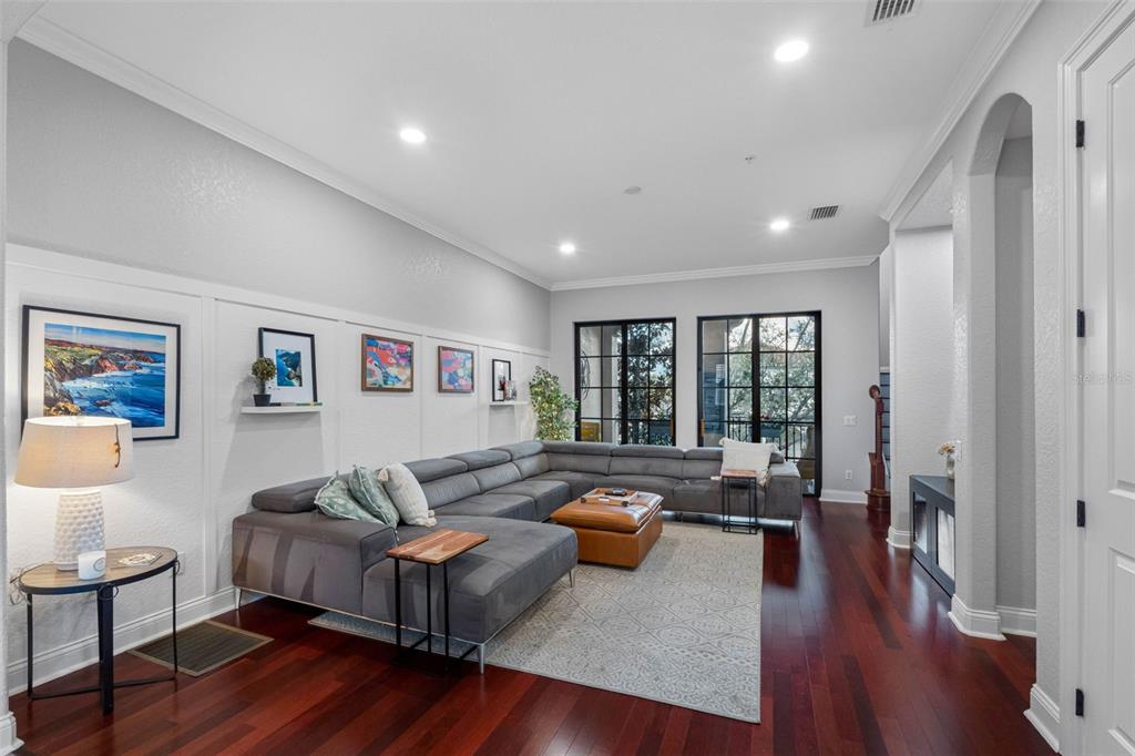 A living room features a large gray sectional sofa, a leather ottoman, and hardwood floors — 6031 BOWEN DANIEL DRIVE UNIT 105, TAMPA, FL