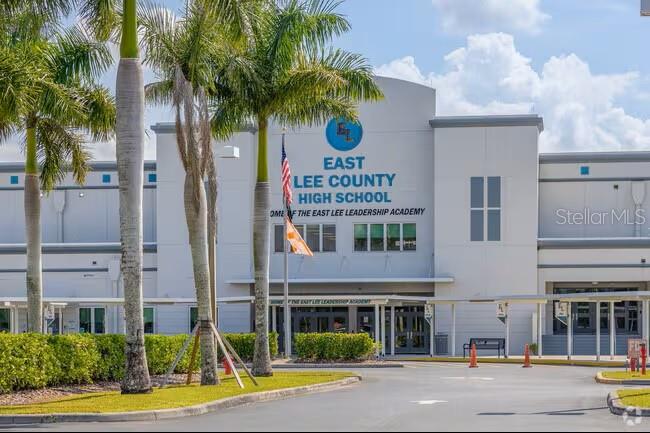The exterior of East Lee County High School features palm trees and a paved driveway — 608 CHEMSTRAND STREET E, LEHIGH ACRES, FL