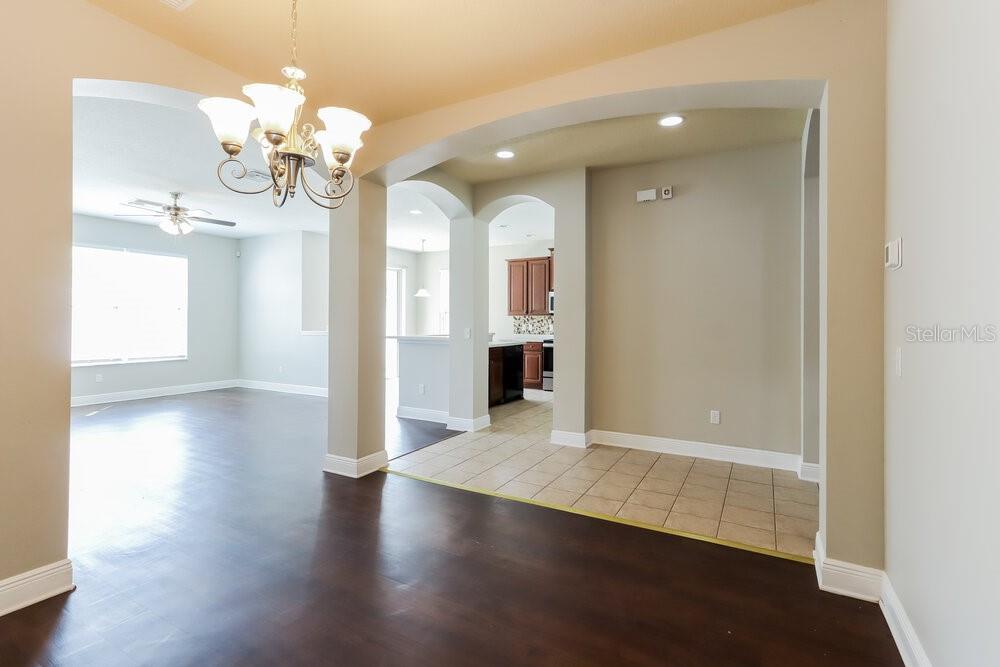 A dining area with dark wood floors transitions into a tiled kitchen with arched entryways — 7935 CAMDEN WOODS DRIVE, TAMPA, FL