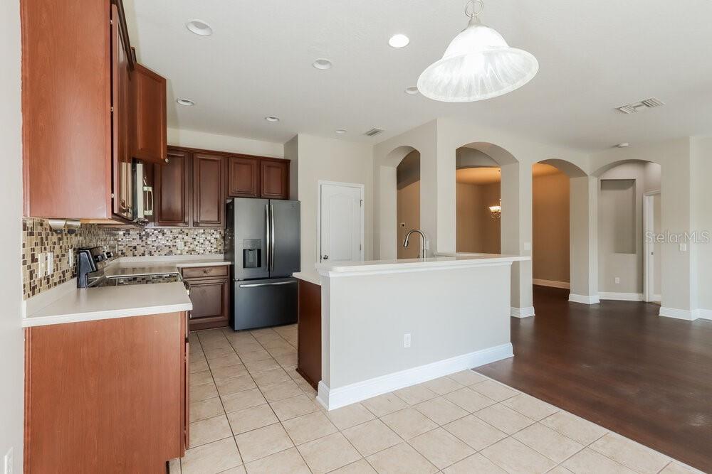 A kitchen with dark wood cabinets, stainless steel appliances, and a tiled floor — 7935 CAMDEN WOODS DRIVE, TAMPA, FL