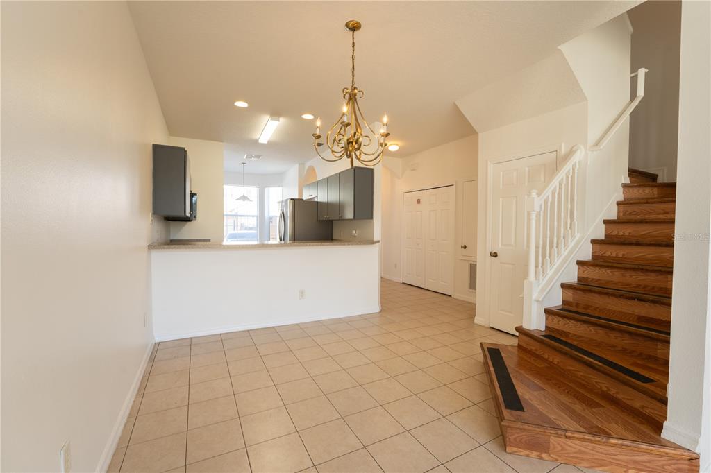 A dining area with tile floors, a chandelier, and a staircase leading to the upper level — 4712 HEMINGWAY HOUSE STREET, KISSIMMEE, FL