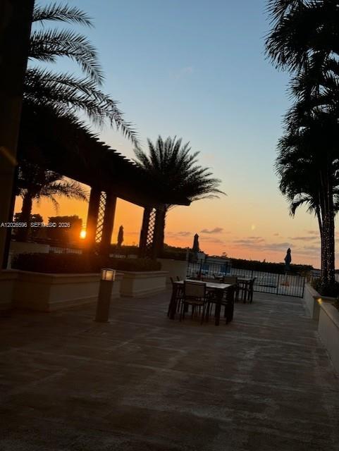 An outdoor patio features a dining table and chairs under a pergola at sunset — 1300 Ponce De Leon Blvd # 702, Coral Gables FL 33134, CORAL GABLES, FL