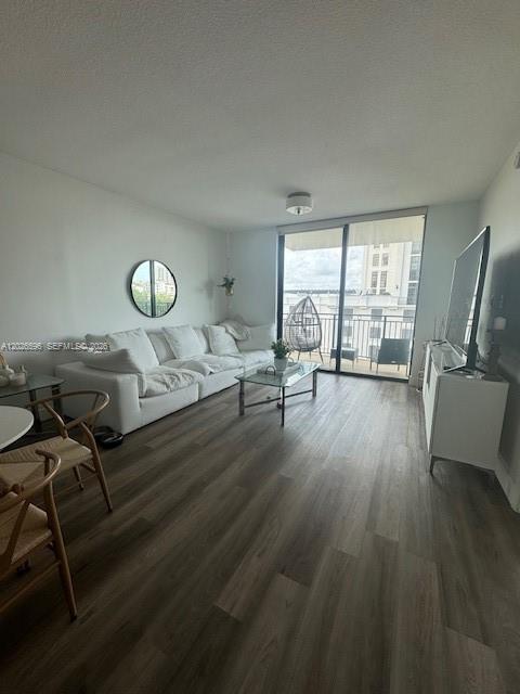 A living room features a white sectional sofa, wood-look flooring, and a glass balcony door — 1300 Ponce De Leon Blvd # 702, Coral Gables FL 33134, CORAL GABLES, FL