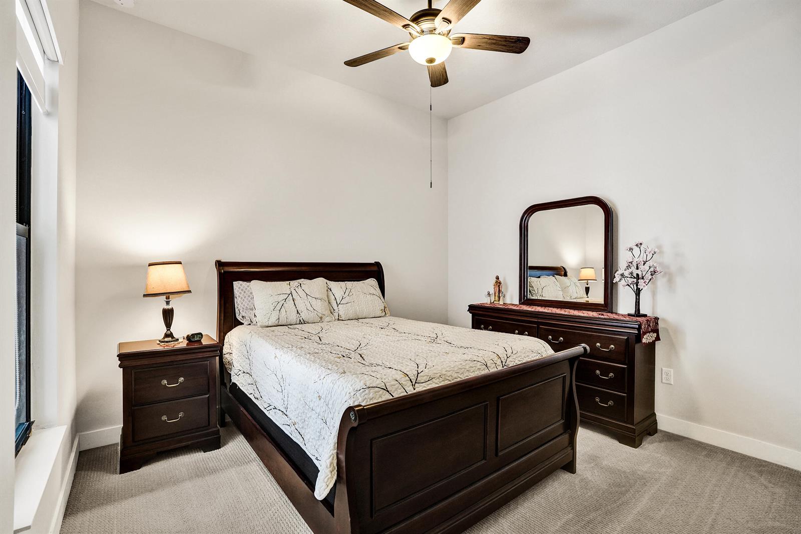 A bedroom features a dark wood bed frame, matching dresser with mirror, and a ceiling fan — 8336 W Blue Spring Drive, Parkland FL 33067, PARKLAND, FL