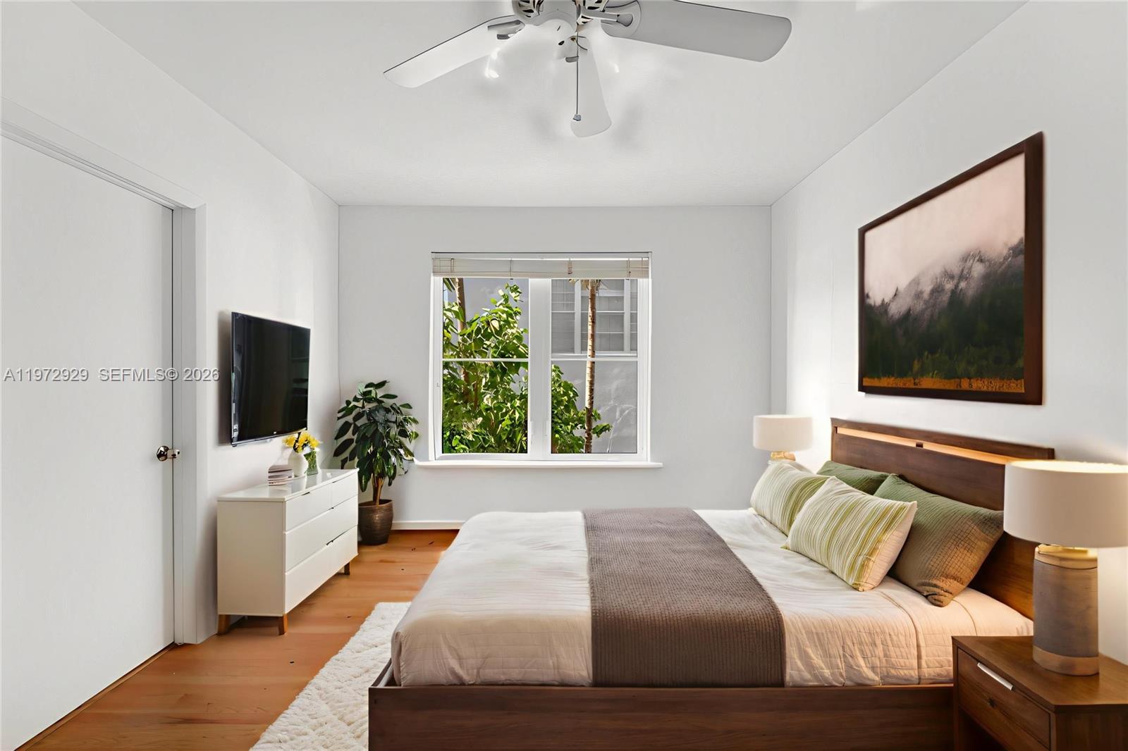 A bedroom features a wooden bed frame, white dresser, ceiling fan, and a window view — 1018 Meridian Ave # 8, Miami Beach FL 33139, MIAMI BEACH, FL