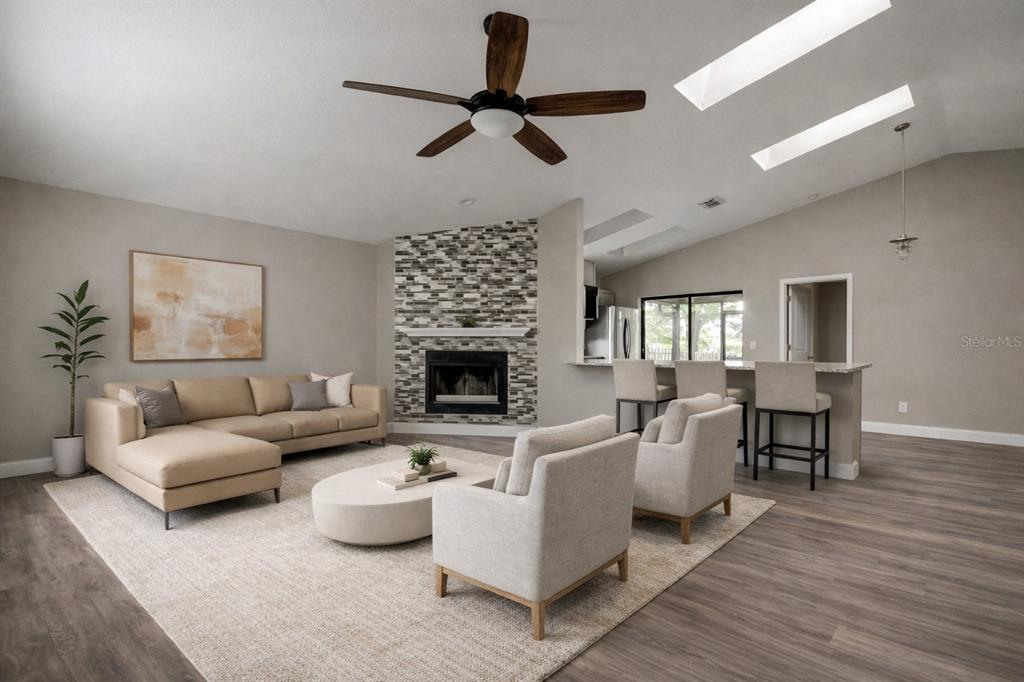 A living room features a stone fireplace, beige sectional sofa, two armchairs, and vaulted ceilings — 206 BEDFORD STREET, OLDSMAR, FL