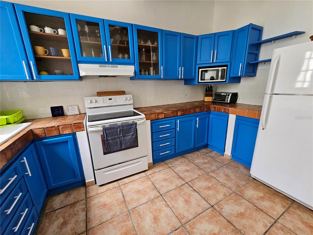 A kitchen features bright blue cabinets, tiled countertops, a white stove, and a white refrigerator — 353 CALLE DE LA LUNA UNIT 301, OLD SAN JUAN, PR