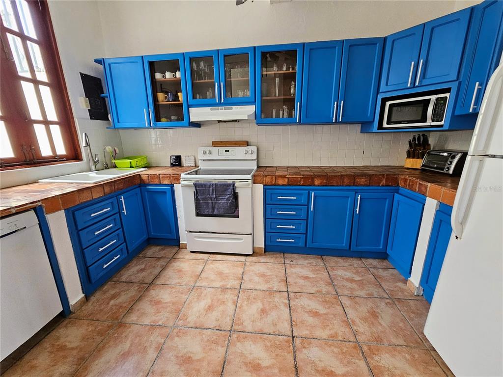 A kitchen features blue cabinets, tiled countertops, a white stove, and a white refrigerator — 353 CALLE DE LA LUNA UNIT 301, OLD SAN JUAN, PR