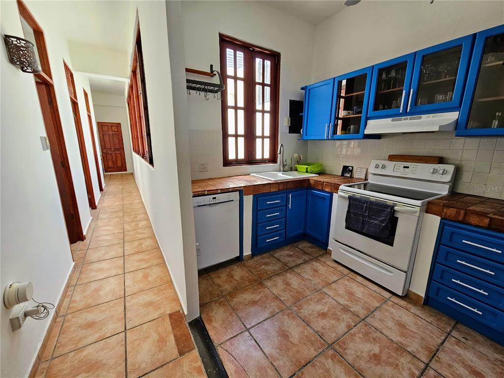 A kitchen features blue cabinets, tiled countertops, a white stove, and a tiled floor — 353 CALLE DE LA LUNA UNIT 301, OLD SAN JUAN, PR