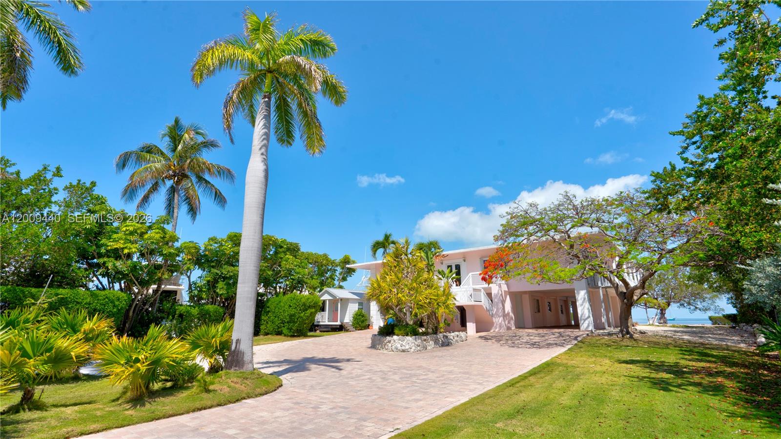 A two-story pink house with a paved driveway and palm trees under a blue sky — 1101 Mastic Street, Islamorada FL 33036, ISLAMORADA, FL
