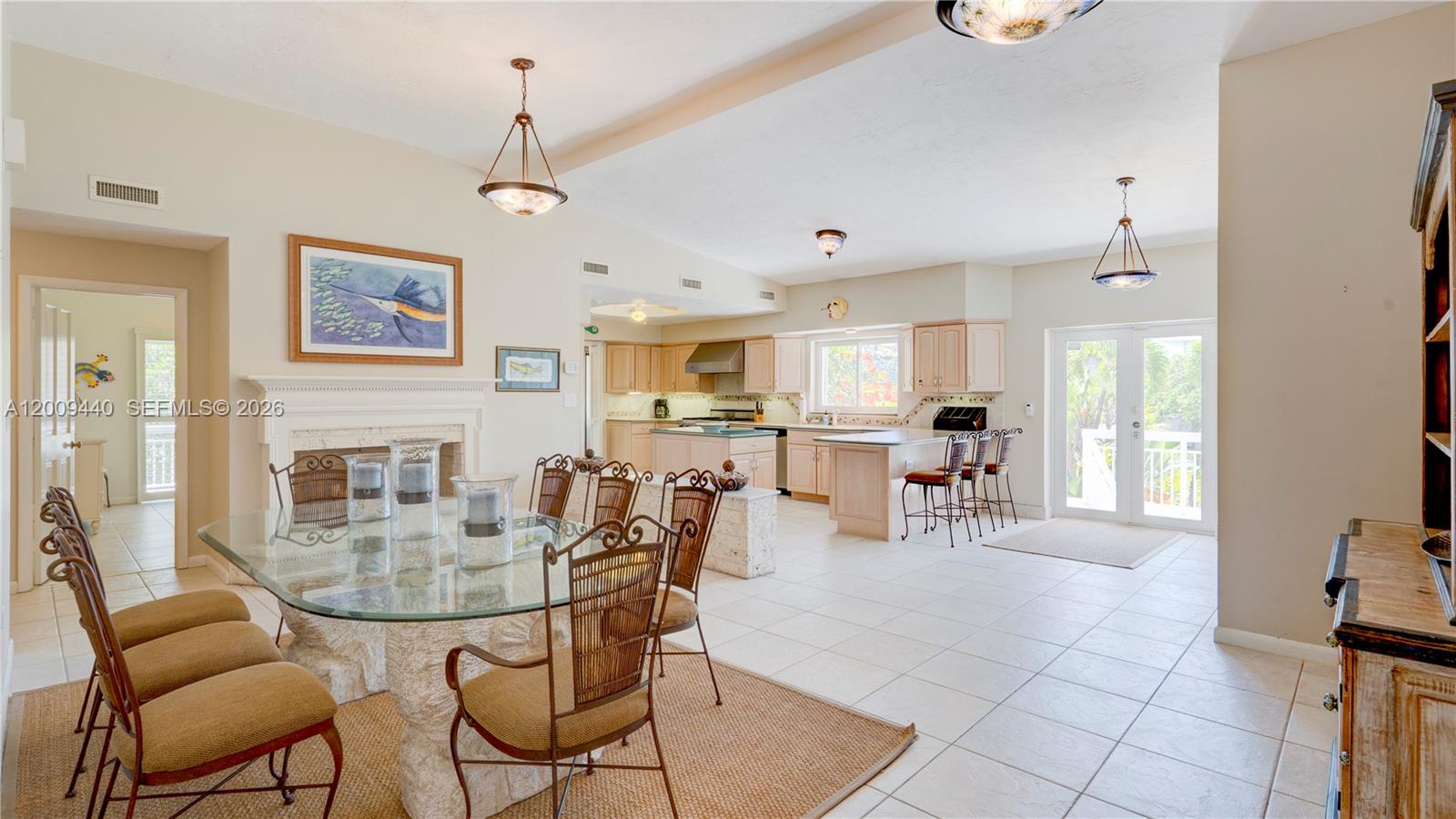 This open-concept dining area features a glass-topped table, tile flooring, and an adjacent kitchen — 1101 Mastic Street, Islamorada FL 33036, ISLAMORADA, FL