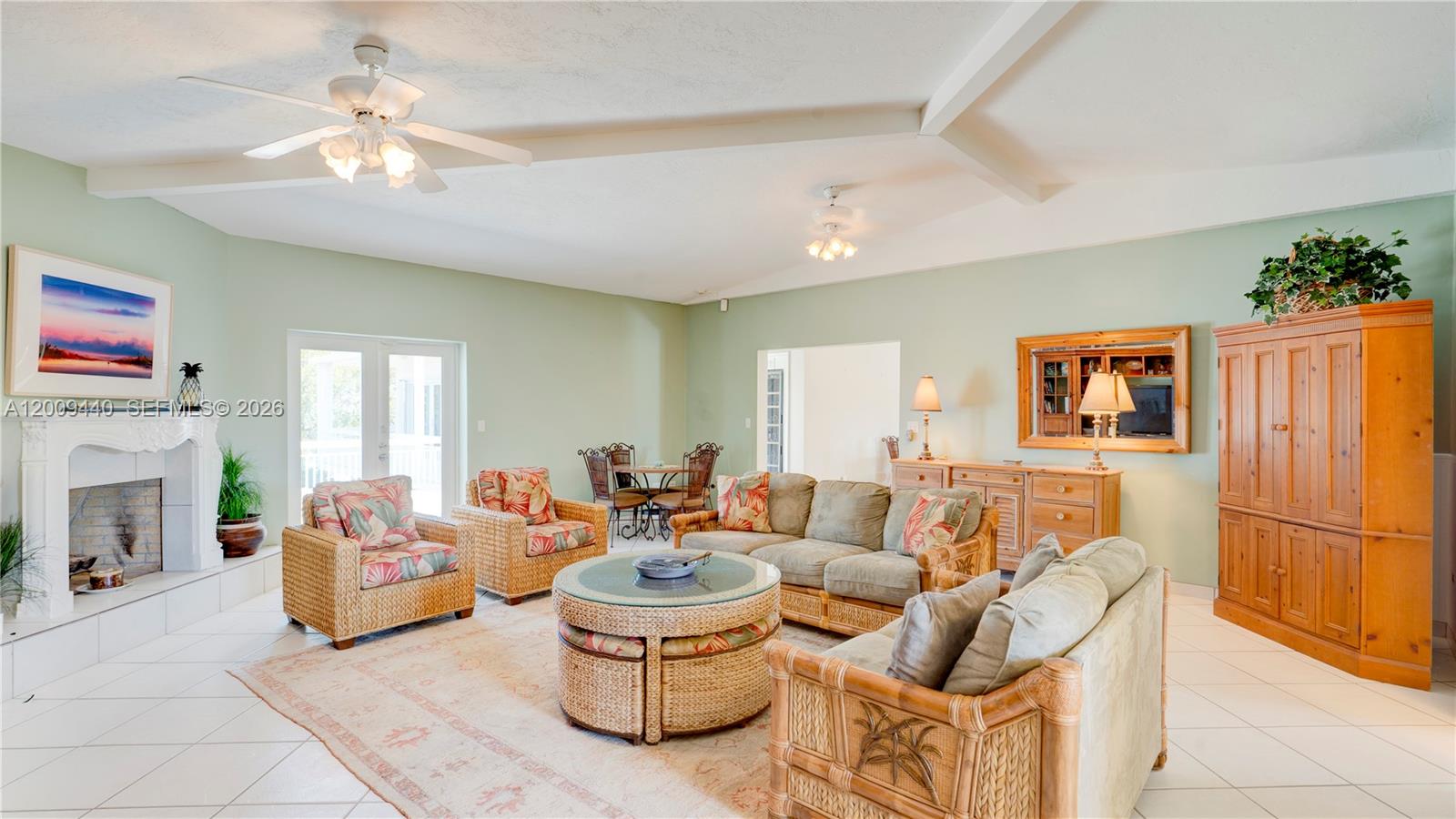 A living room features wicker furniture, a fireplace, and light green walls with tile flooring — 1101 Mastic Street, Islamorada FL 33036, ISLAMORADA, FL