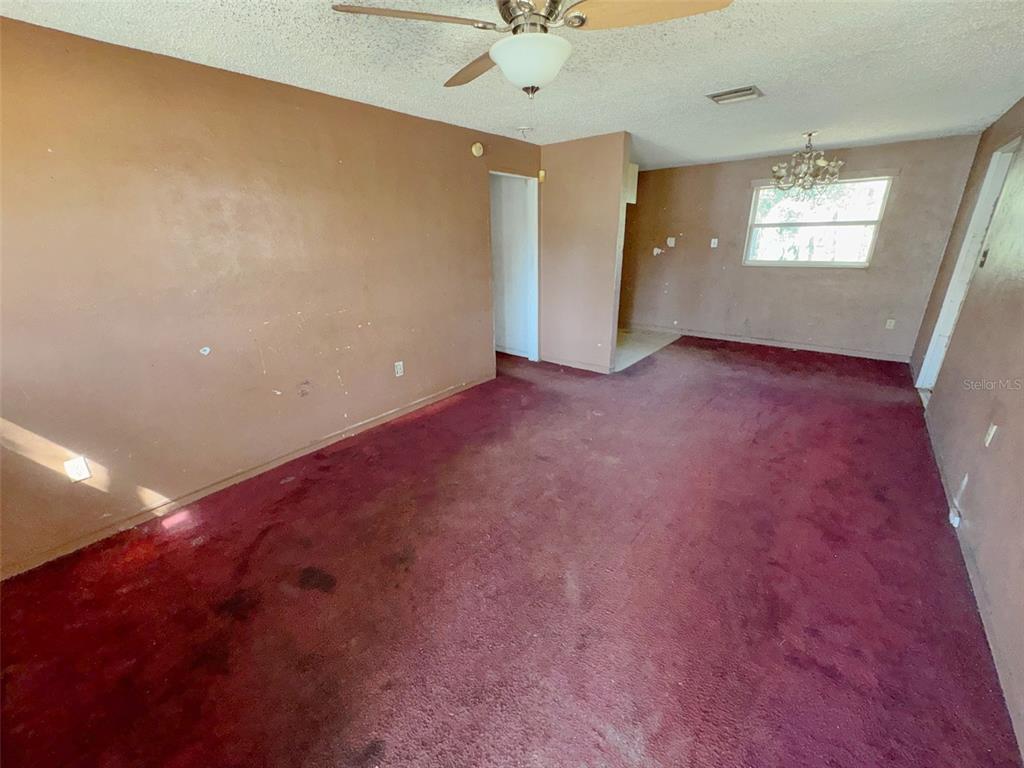A room with brown walls, dark red carpeting, a ceiling fan, and a chandelier — 2841 W AMELIA STREET, ORLANDO, FL