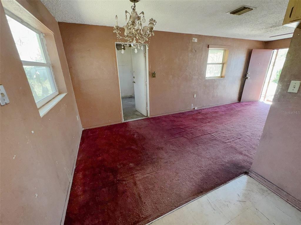 A room with brown walls, red carpeting, a crystal chandelier, and an open doorway — 2841 W AMELIA STREET, ORLANDO, FL