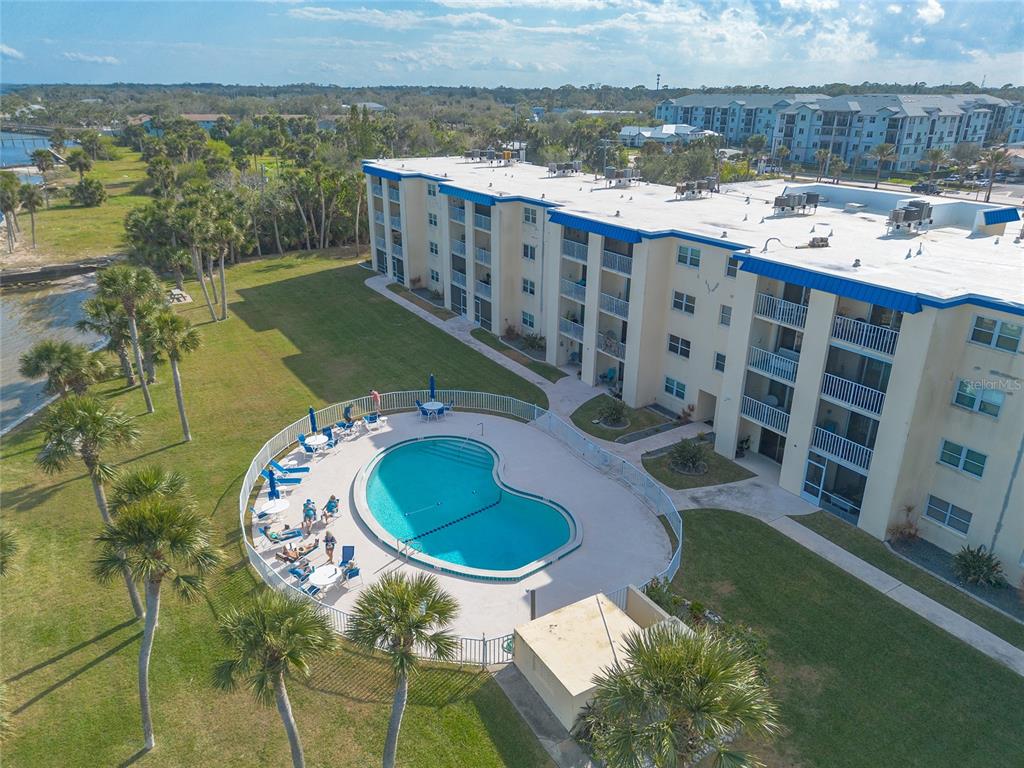 An aerial view shows a multi-story apartment building with a kidney-shaped pool and palm trees — 3131 S RIDGEWOOD AVENUE UNIT 101, SOUTH DAYTONA, FL