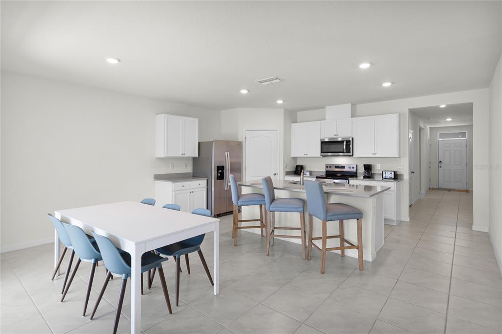 A kitchen with white cabinets, stainless steel appliances, and a dining table with blue chairs — 1340 DAISY FIEL DR, WINTER HAVEN, FL