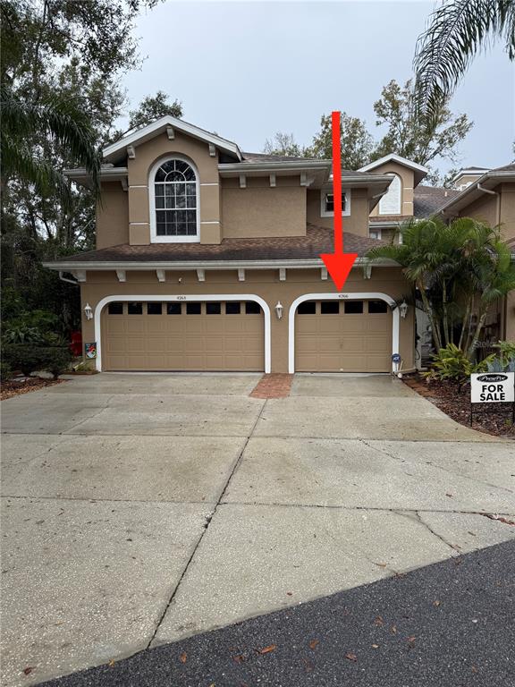 A two-story stucco house features two separate garage bays and a concrete driveway — 4266 PRESERVE PLACE UNIT 4266, PALM HARBOR, FL