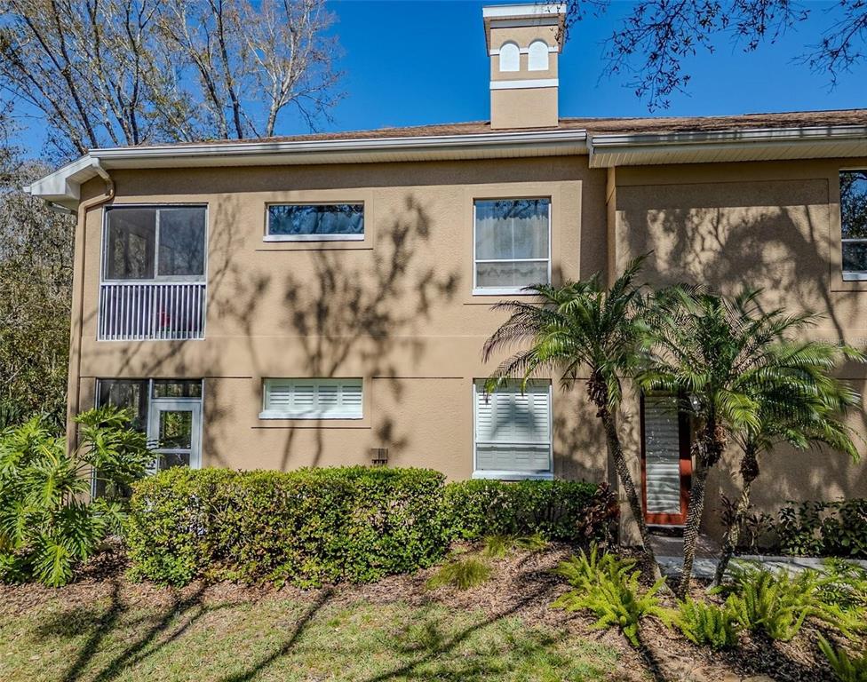 A two-story tan stucco townhouse exterior with a chimney, screened balcony, and landscaped front yard — 4266 PRESERVE PLACE UNIT 4266, PALM HARBOR, FL