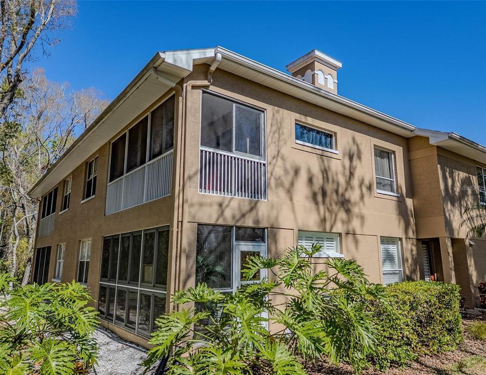 A two-story tan stucco building features screened-in porches on both levels and a chimney — 4266 PRESERVE PLACE UNIT 4266, PALM HARBOR, FL