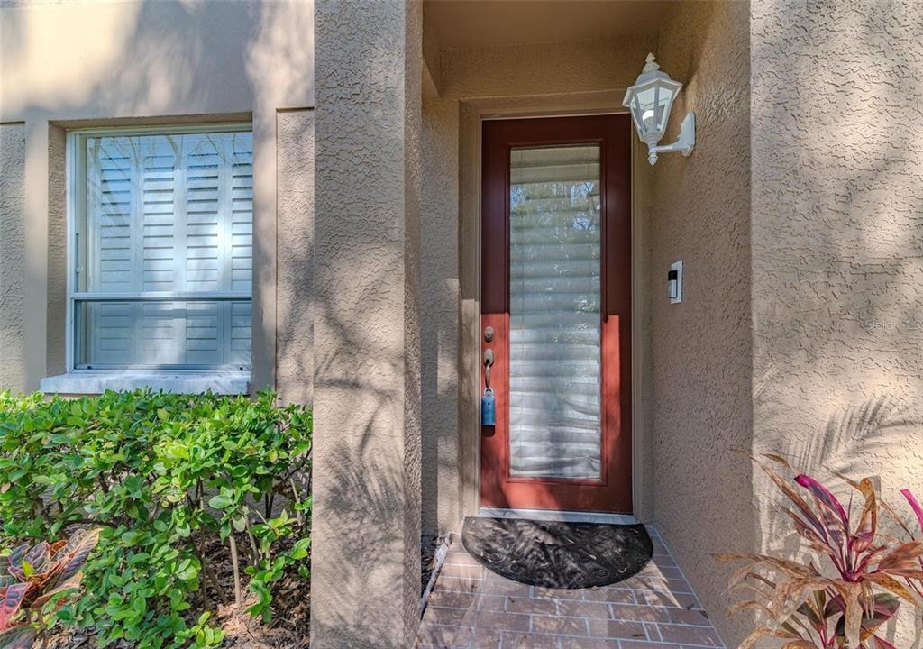 A front entrance with a red door, a window with blinds, and a small porch — 4266 PRESERVE PLACE UNIT 4266, PALM HARBOR, FL