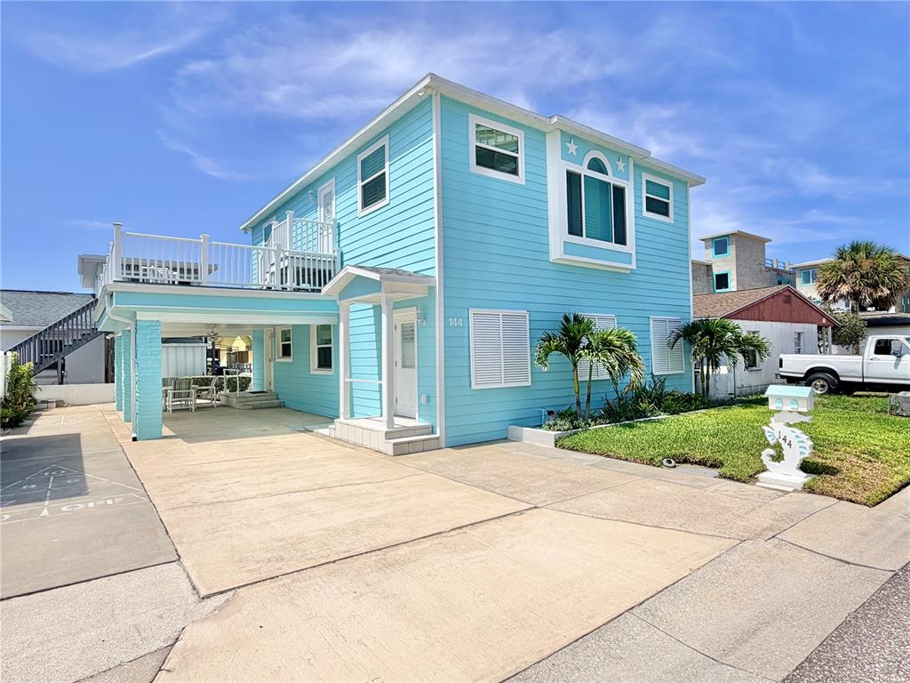 A two-story light blue house with a covered carport and a white picket fence — 144 CORAL AVENUE, REDINGTON SHORES, FL