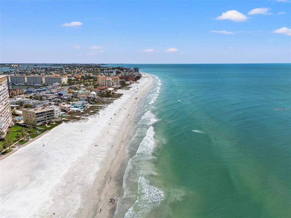 An aerial view shows a sandy beach along the ocean with coastal buildings nearby — 144 CORAL AVENUE, REDINGTON SHORES, FL