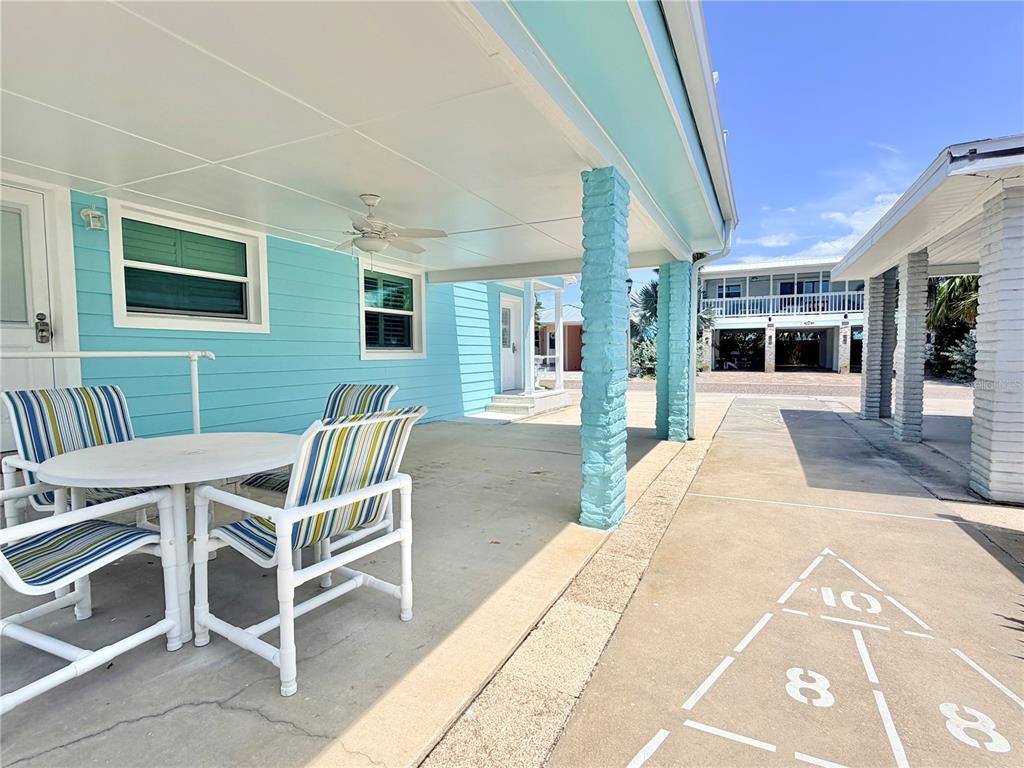 A patio with a table and chairs sits beside a shuffleboard court under a carport — 144 CORAL AVENUE, REDINGTON SHORES, FL