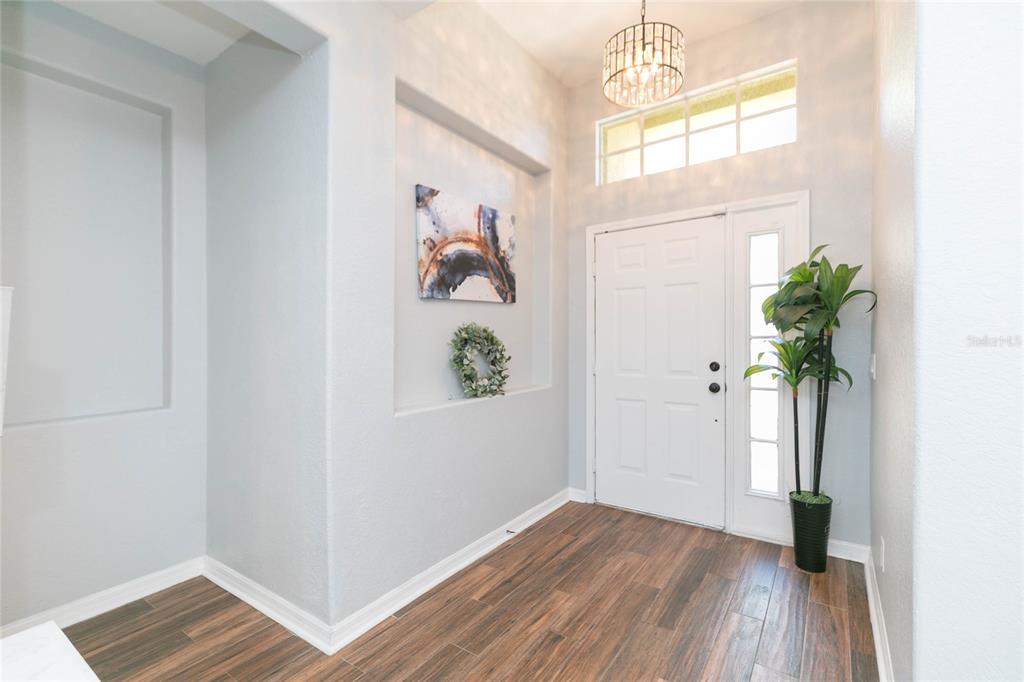 A bright entryway features wood-look tile flooring, a recessed wall niche, and a glass-paneled door — 11334 BRIDGE PINE DRIVE, RIVERVIEW, FL