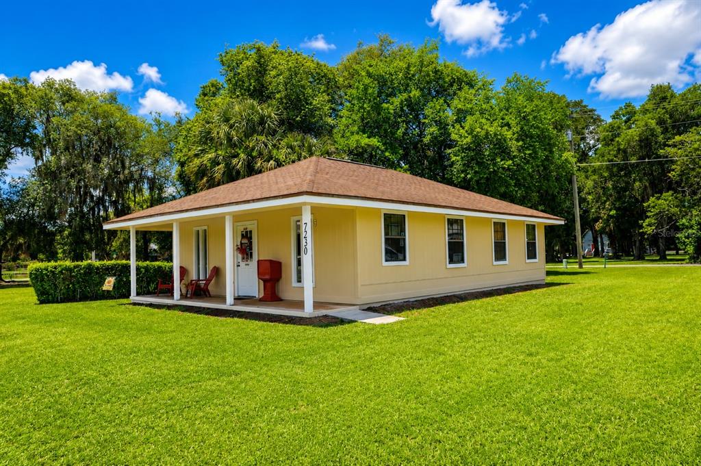 A yellow, single-story house with a covered front porch sits on a grassy lawn — 7230 SE US HIGHWAY 301, HAWTHORNE, FL