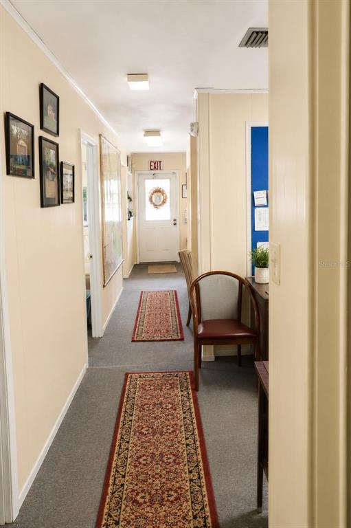 A hallway with gray carpet, two patterned runners, and a door with an exit sign — 7230 SE US HIGHWAY 301, HAWTHORNE, FL