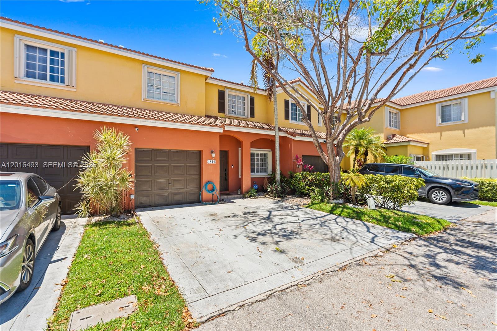 The exterior of a two-story townhouse features orange and yellow stucco walls and a garage — 1844 SW 102nd Way, Miramar FL 33025, MIRAMAR, FL