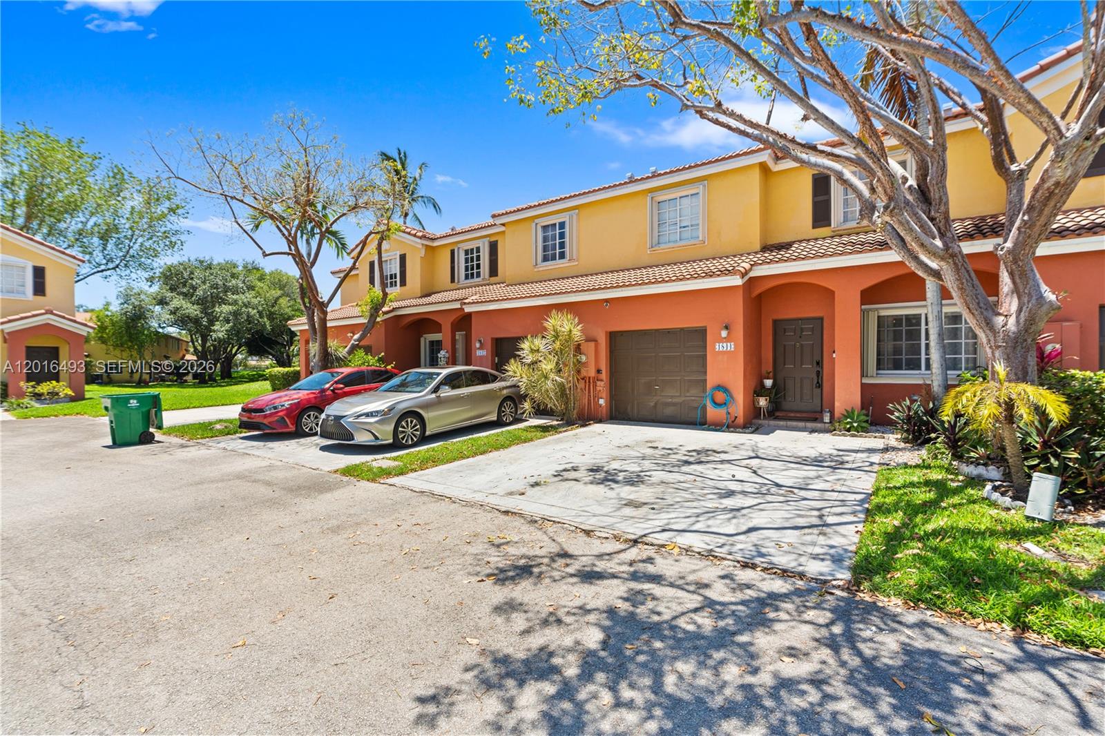 A two-story townhouse exterior features a garage, a driveway with two cars, and orange stucco — 1844 SW 102nd Way, Miramar FL 33025, MIRAMAR, FL