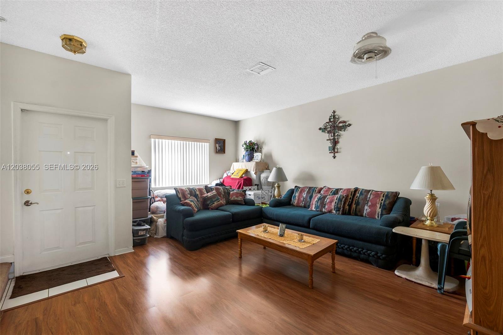 A living room features dark blue sofas, a wooden coffee table, and wood-look flooring — 783 NW 42nd Pl, Deerfield Beach FL 33064, DEERFIELD BEACH, FL
