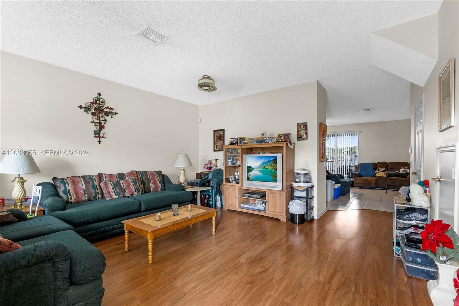 A living room features a dark green sofa, wood coffee table, and wood-look flooring — 783 NW 42nd Pl, Deerfield Beach FL 33064, DEERFIELD BEACH, FL