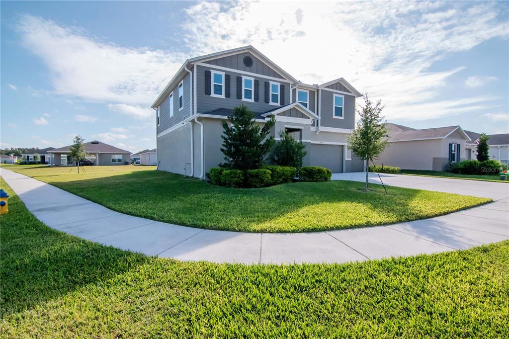 A two-story suburban house with a gray exterior, a two-car garage, and a lawn — 6384 BURNING OPAL BEND, LAND O LAKES, FL