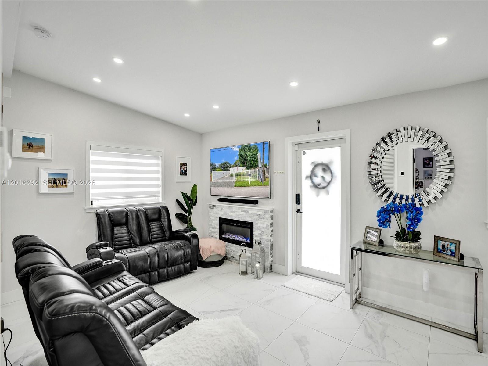 A living room features black leather recliners, a fireplace with a television, and white tile — 10222 SW 181st St, Miami FL 33157, MIAMI, FL