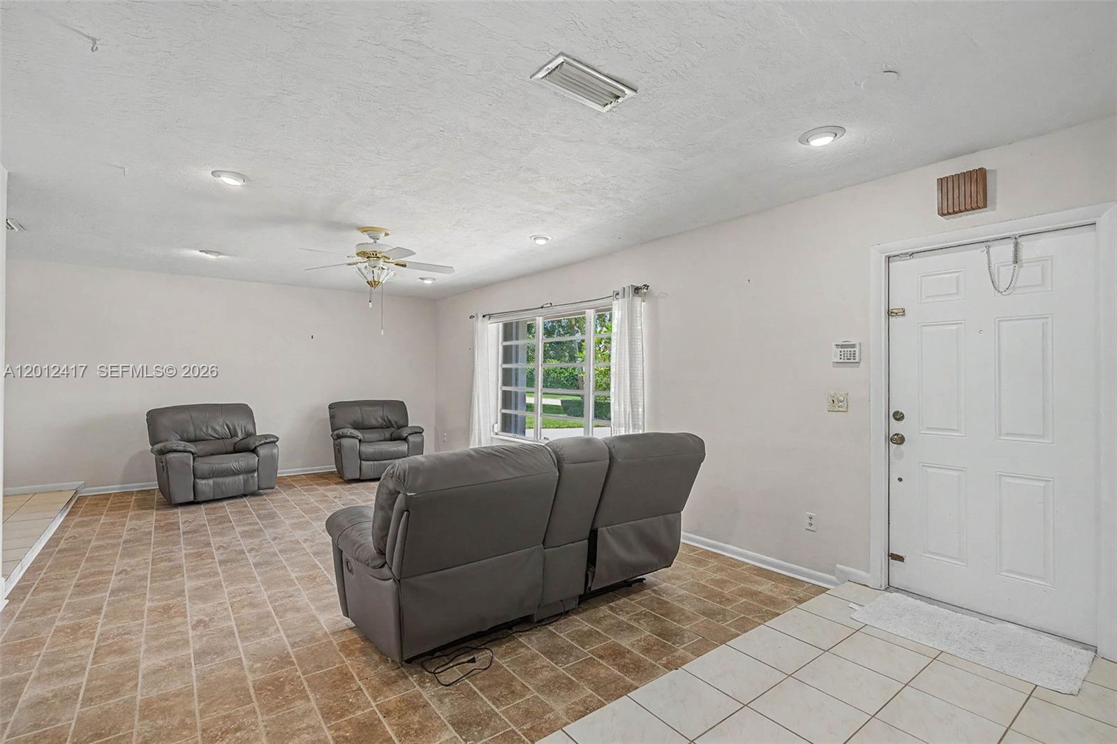 A living room features gray leather furniture, tile flooring, a ceiling fan, and a front door — 11380 SW 131st St, Miami FL 33176, MIAMI, FL