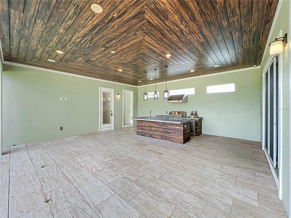 An outdoor kitchen features a wood-paneled vaulted ceiling, light green walls, and tile flooring — 13450 GABOR AVENUE, ORLANDO, FL