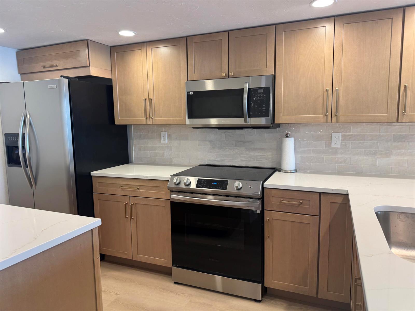 A kitchen features light wood cabinets, stainless steel appliances, white countertops, and a tiled backsplash — 12 Royal Palm Way # 2050, Boca Raton FL 33432, BOCA RATON, FL
