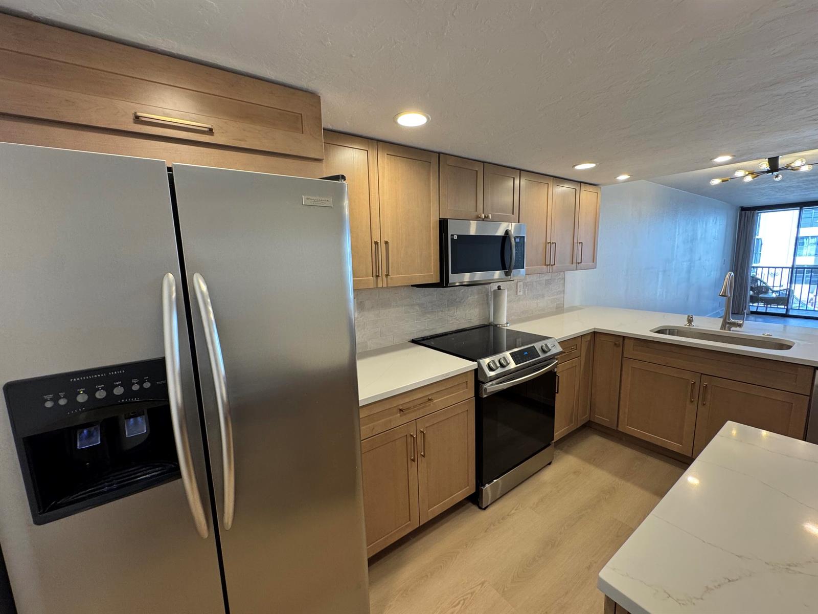 A modern kitchen features light wood cabinets, stainless steel appliances, and white quartz countertops — 12 Royal Palm Way # 2050, Boca Raton FL 33432, BOCA RATON, FL