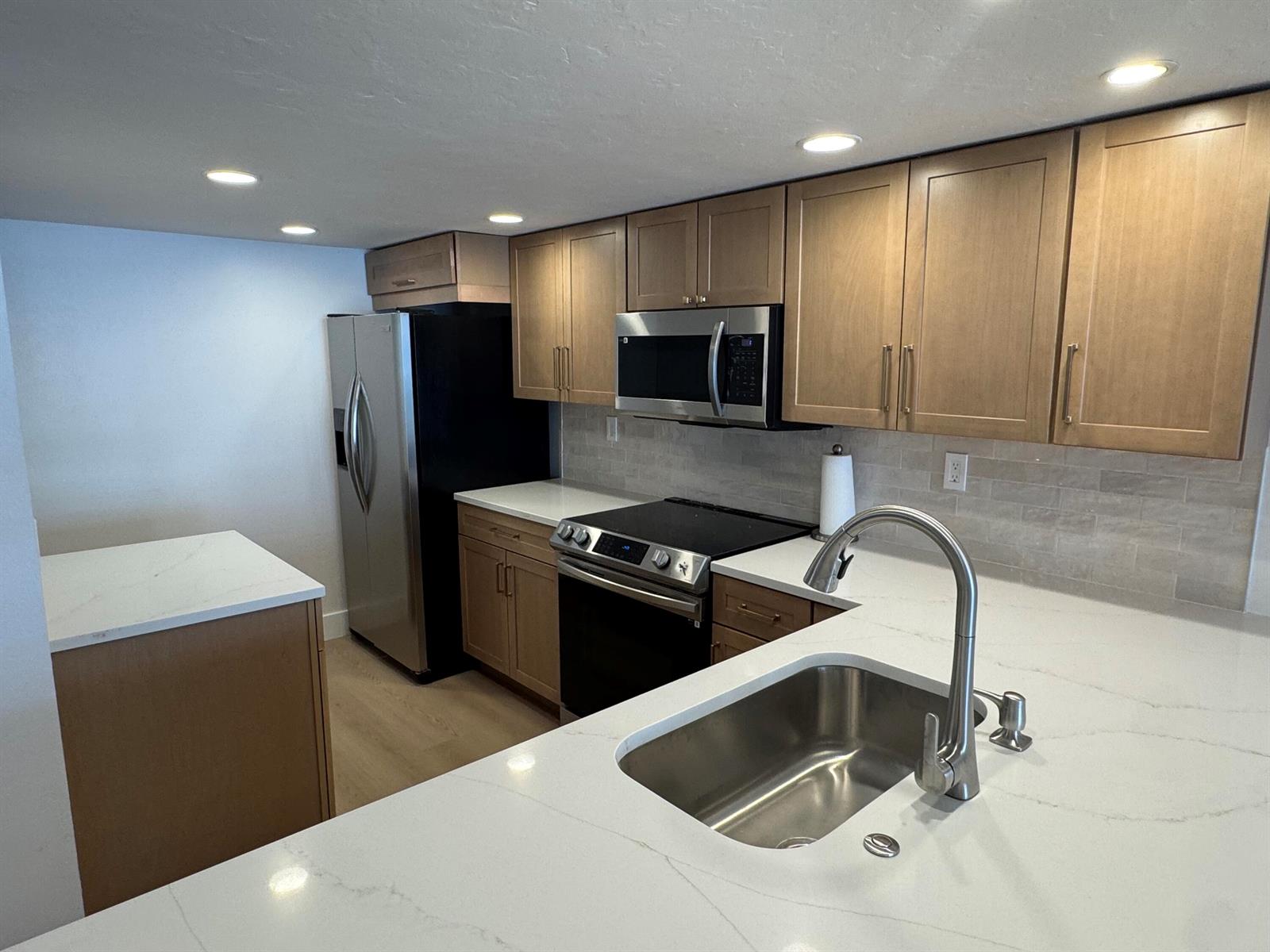A kitchen features light wood cabinets, white quartz countertops, stainless steel appliances, and a sink — 12 Royal Palm Way # 2050, Boca Raton FL 33432, BOCA RATON, FL