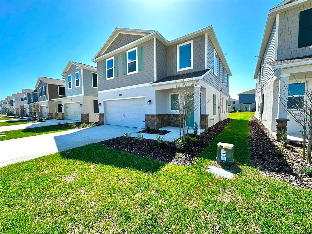 A row of two-story suburban houses with garages and green lawns under a clear sky — 3874 AMERS LOOP, HAINES CITY, FL