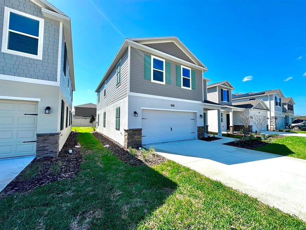 A two-story suburban house with a two-car garage and gray siding under a blue sky — 3874 AMERS LOOP, HAINES CITY, FL